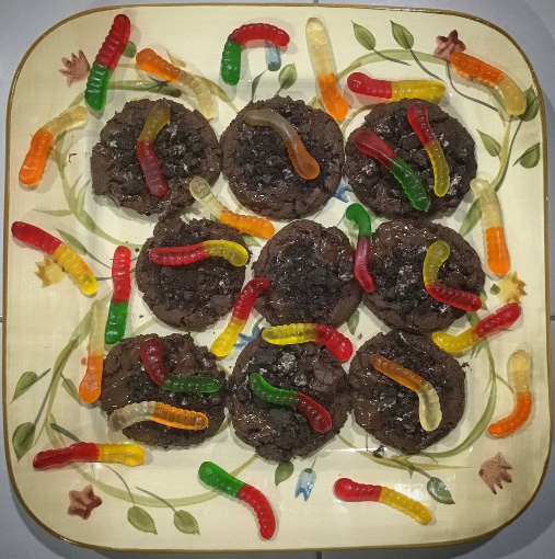 Cookies decorated with Oreo crumbs and Gummi Worms on top of a flowery, Earth Day-themed dish