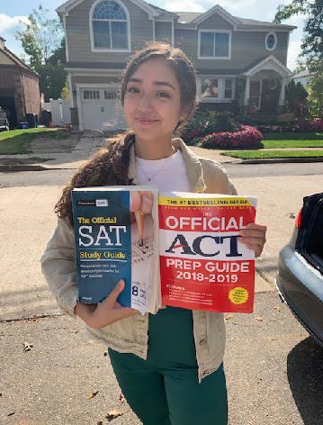 Senior Maria Russotti holding up practice books for the SAT and ACT 