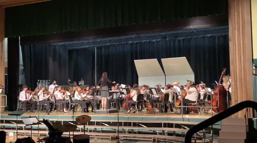 The orchestra, conducted by Alyssa White, performs for the audience