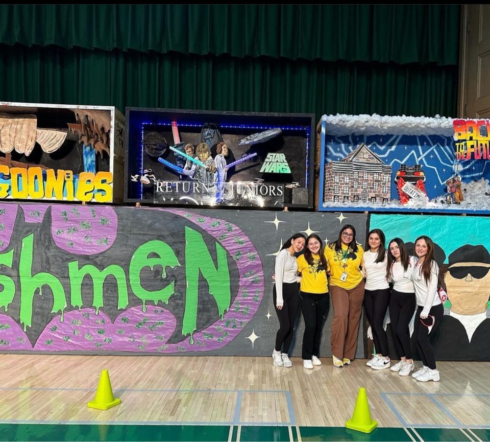 Freshmen and class advisors pose in front of their completed banner. 