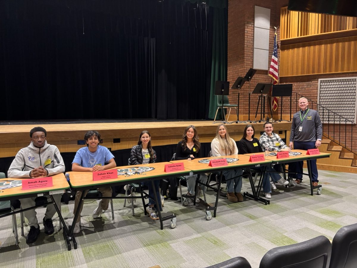 Seven LHS alumni sit at panel in auditorium awaiting their presentation to the junior class. Image courtesy of Ms. Sue Moller.